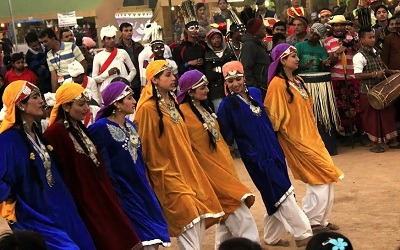 Women wearing blue yellow and red outfits performing rouf