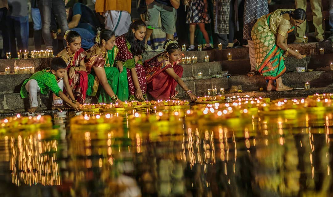 Women sending diyas to float on the river