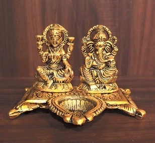 A Diya with Lord Ganesh and Lakshmi idols made from metal